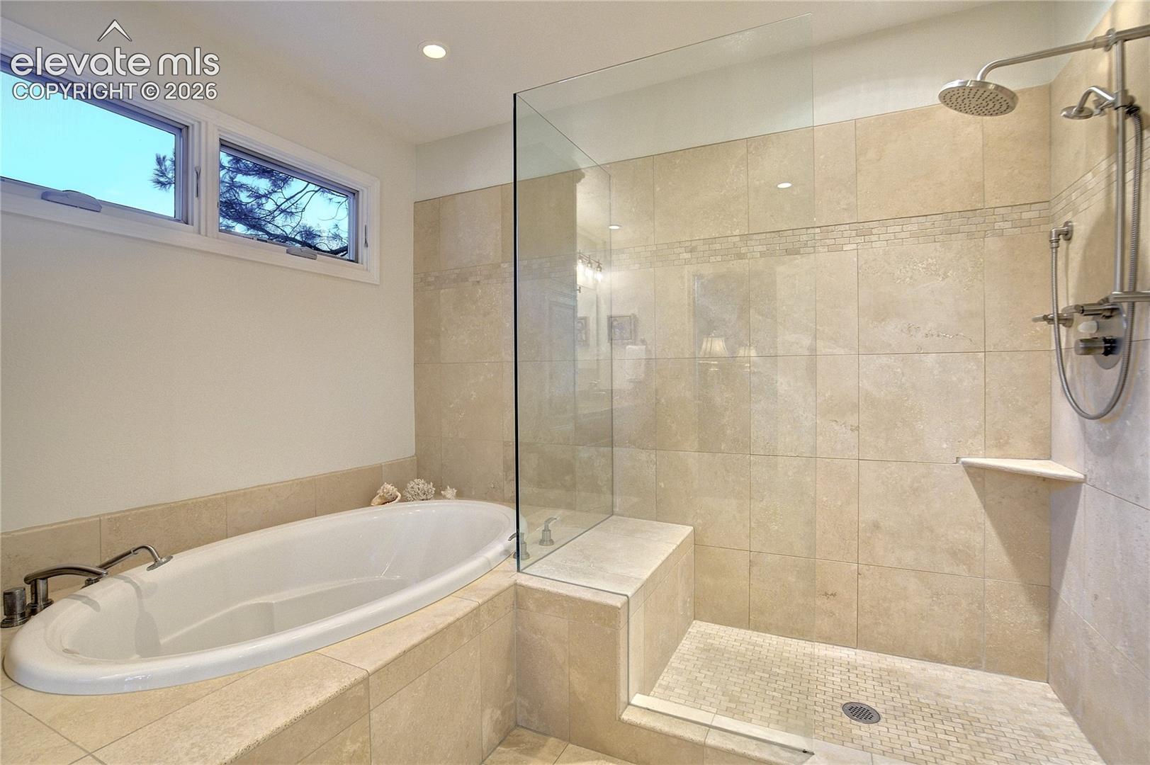 An oversized frameless shower with bench, rainfall + handheld showerheads joins the soaking tub in this spacious 5-piece bath.