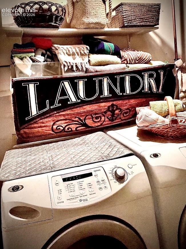 Dedicated laundry space featuring a white front-loading washer and dryer, integrated shelving, and wall-mounted storage baskets