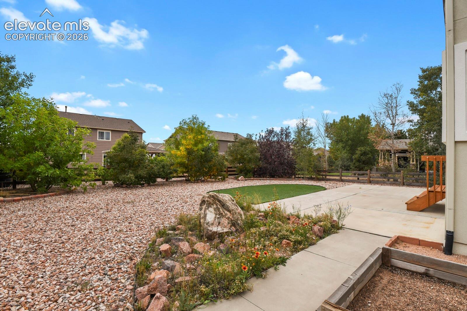 Expansive outdoor area featuring a concrete patio, stepping stones, and a rock-mulched landscape bed with plantings