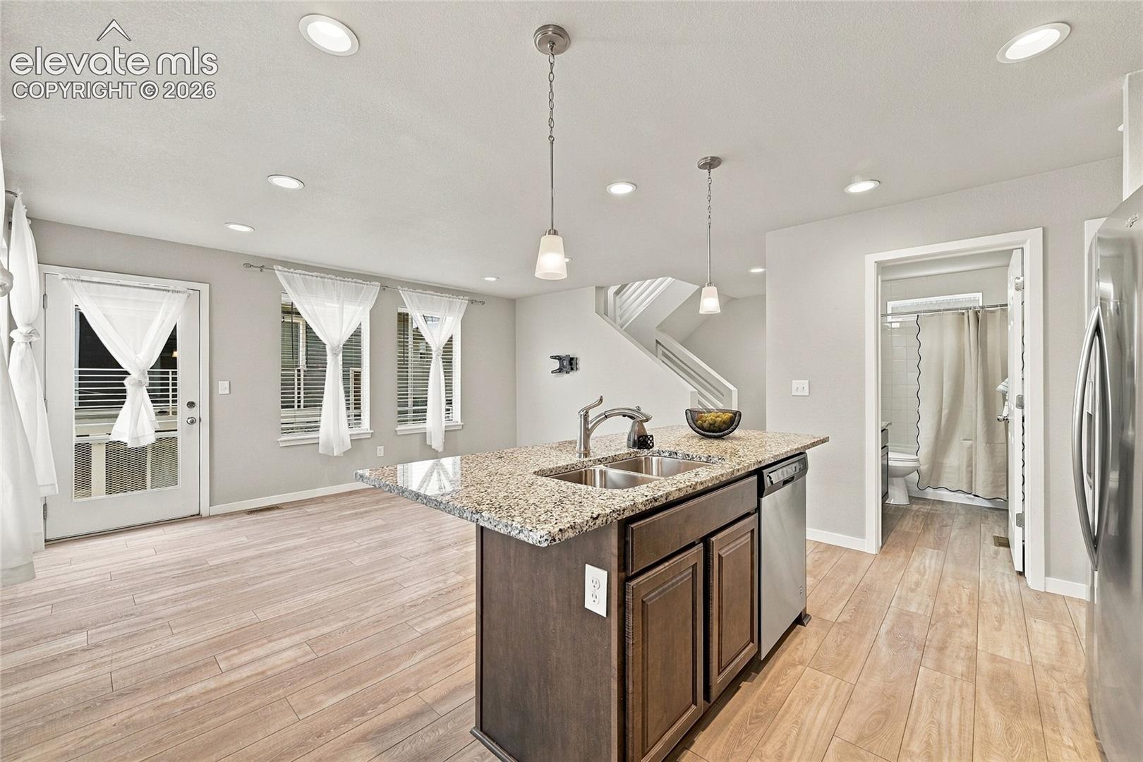 Kitchen island with granite countertop, double basin sink, and stainless steel dishwasher