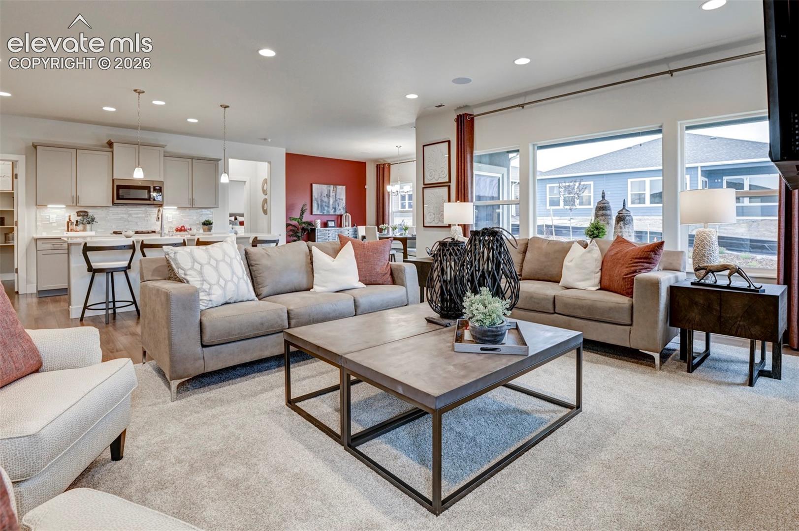 Open-concept living space featuring recessed lighting, a kitchen island with seating, a built-in microwave, and large windows