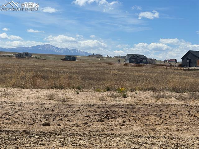 Expansive land with distant mountain views, featuring a clear sky with scattered clouds
