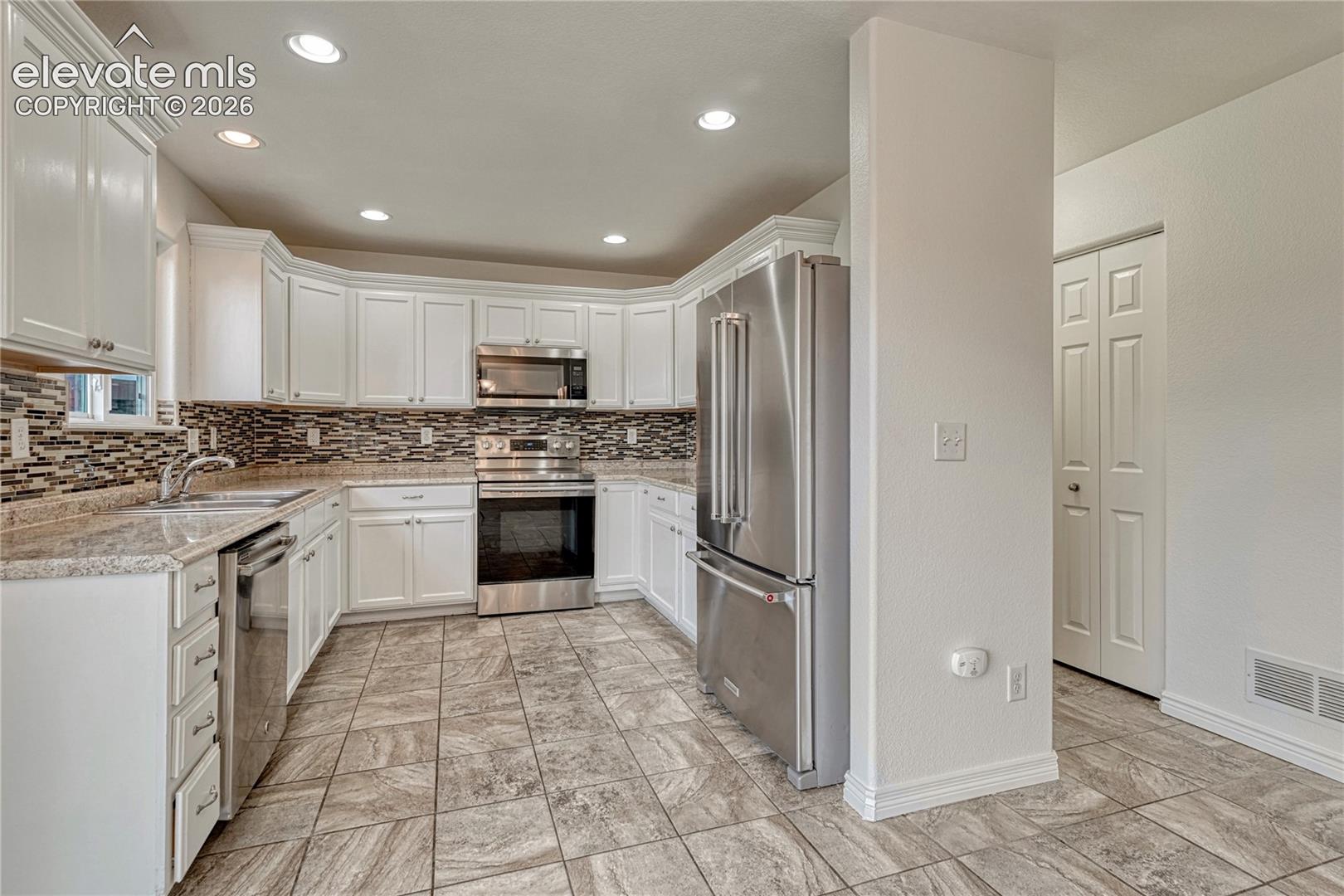 Kitchen has tile flooring, stainless steel appliances...