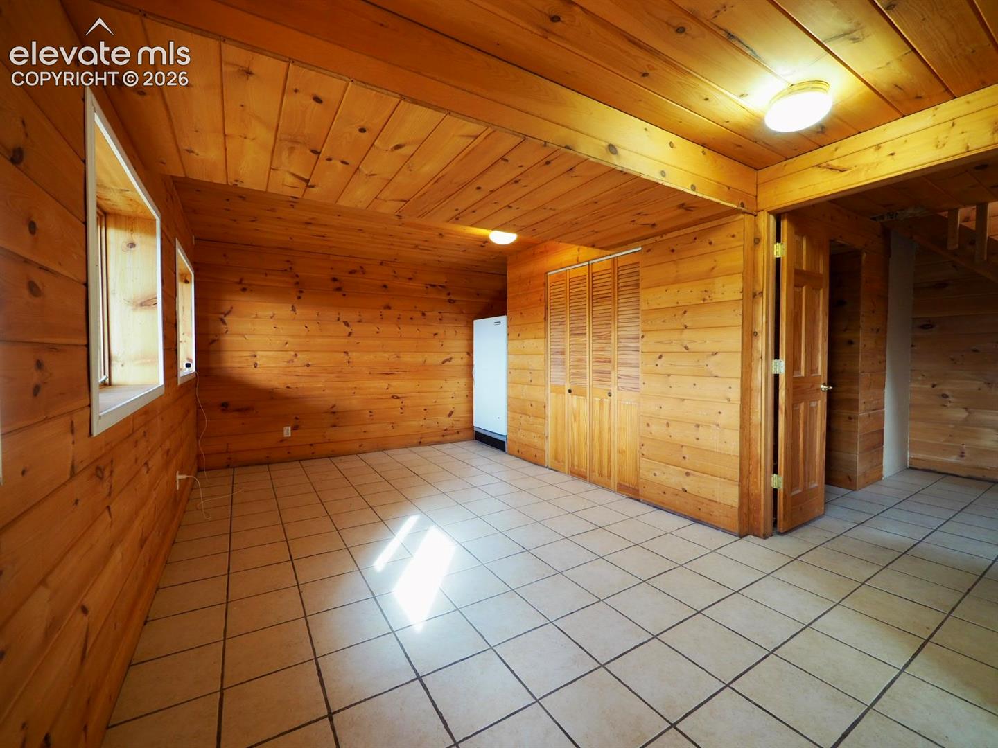 Room featuring wood-plank walls and ceilings, ceramic tile flooring, built-in louvered-door closets, and recessed lighting