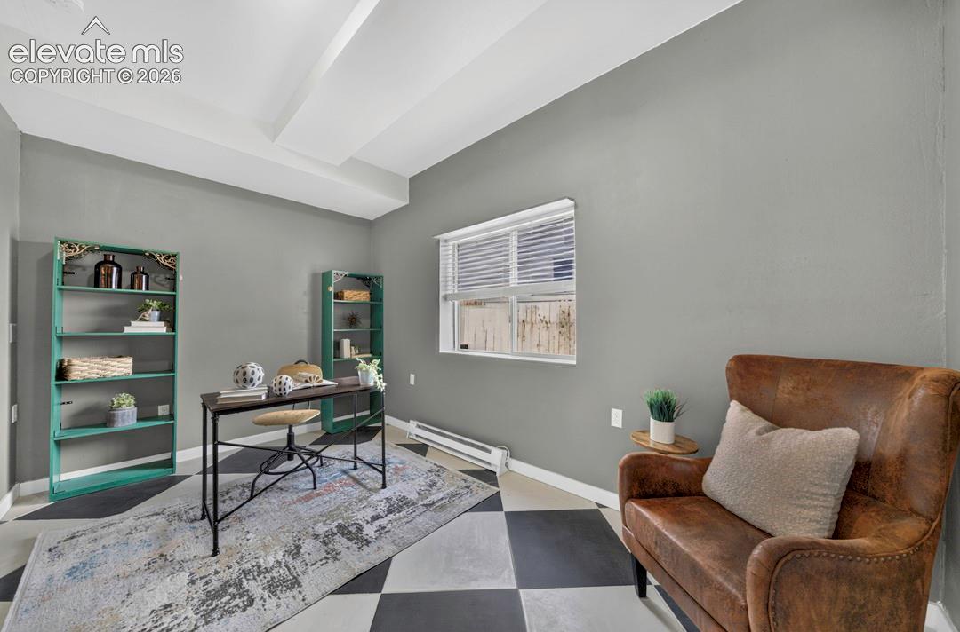 Room featuring high ceilings with boxed beam architectural detailing, geometric-patterned flooring, and a window with horizontal blinds