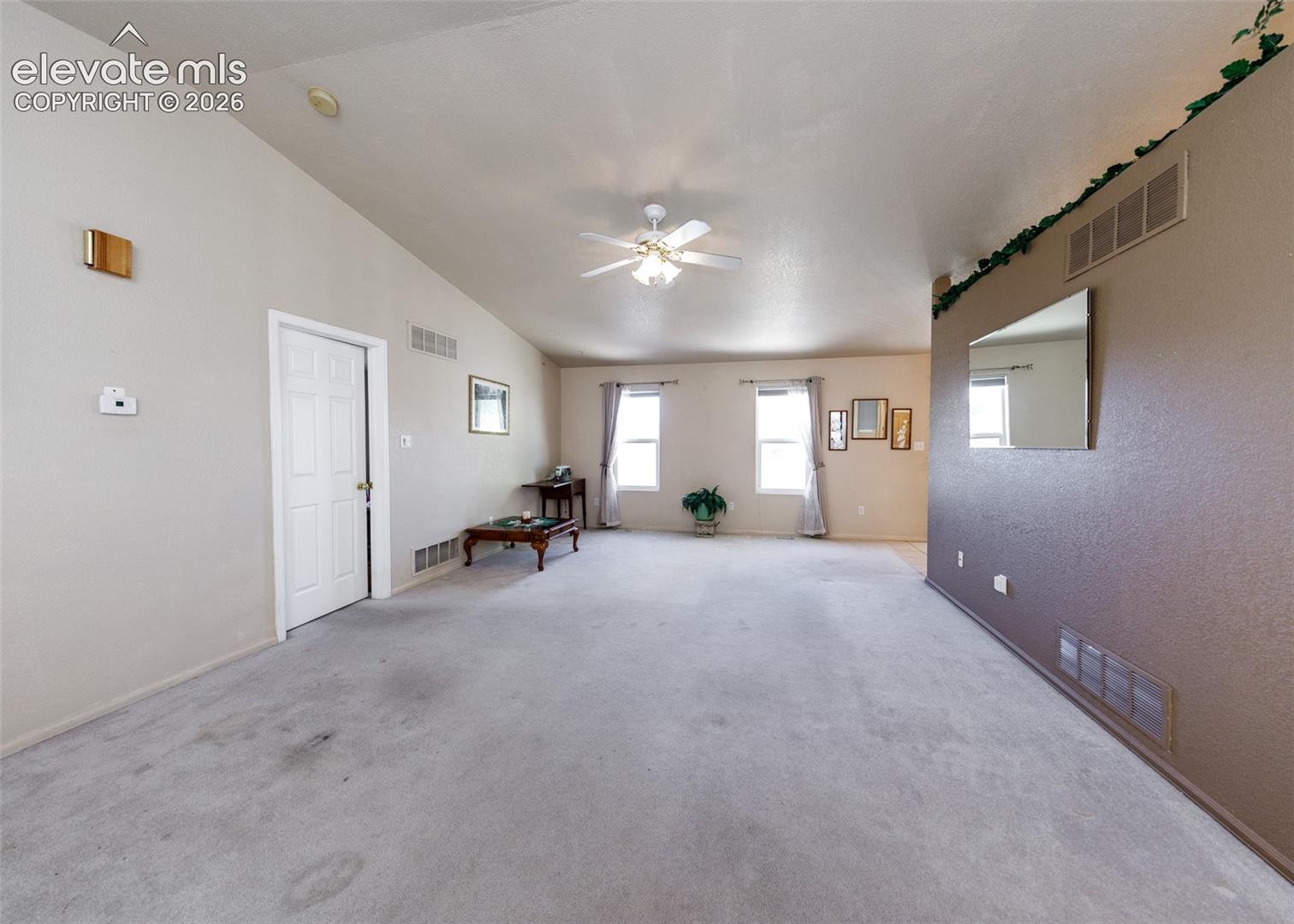 Vaulted ceilings, carpeted flooring, ceiling-mounted fan with integrated lighting, dual windows, and wall-mounted mirror