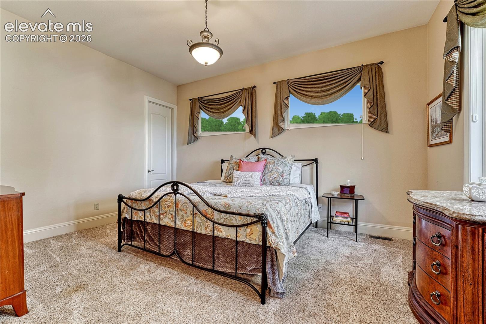 Room featuring neutral wall tones, wall-to-wall carpeting, dual horizontal windows, and an overhead pendant light fixture