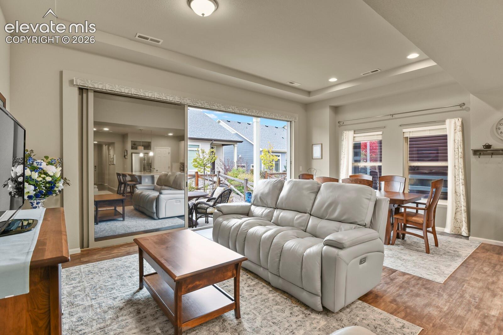 Tray ceiling, recessed lighting, wood-finish luxury tile flooring, and a 17' wide sliding glass door