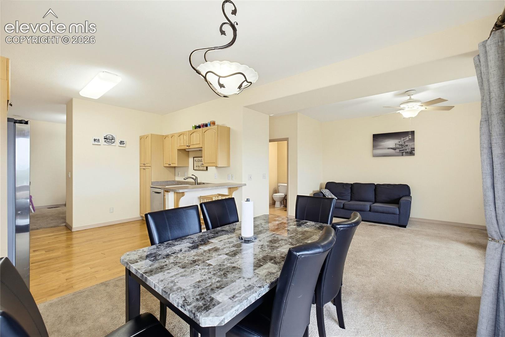 Open-concept living space with wood-finish flooring, recessed lighting, ceiling fan, and built-in kitchen cabinetry