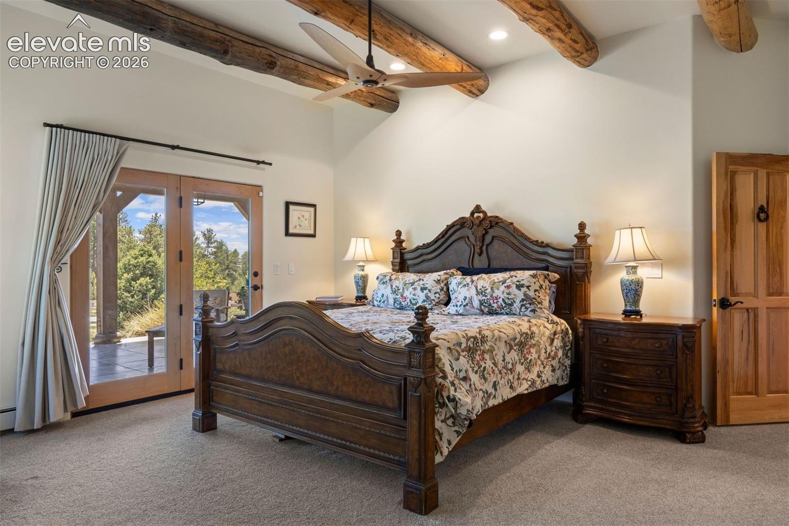 Primary suite with natural hand-hewn beams, glass door walk out to a private covered patio, and two separate bathrooms, a luxurious detail. 