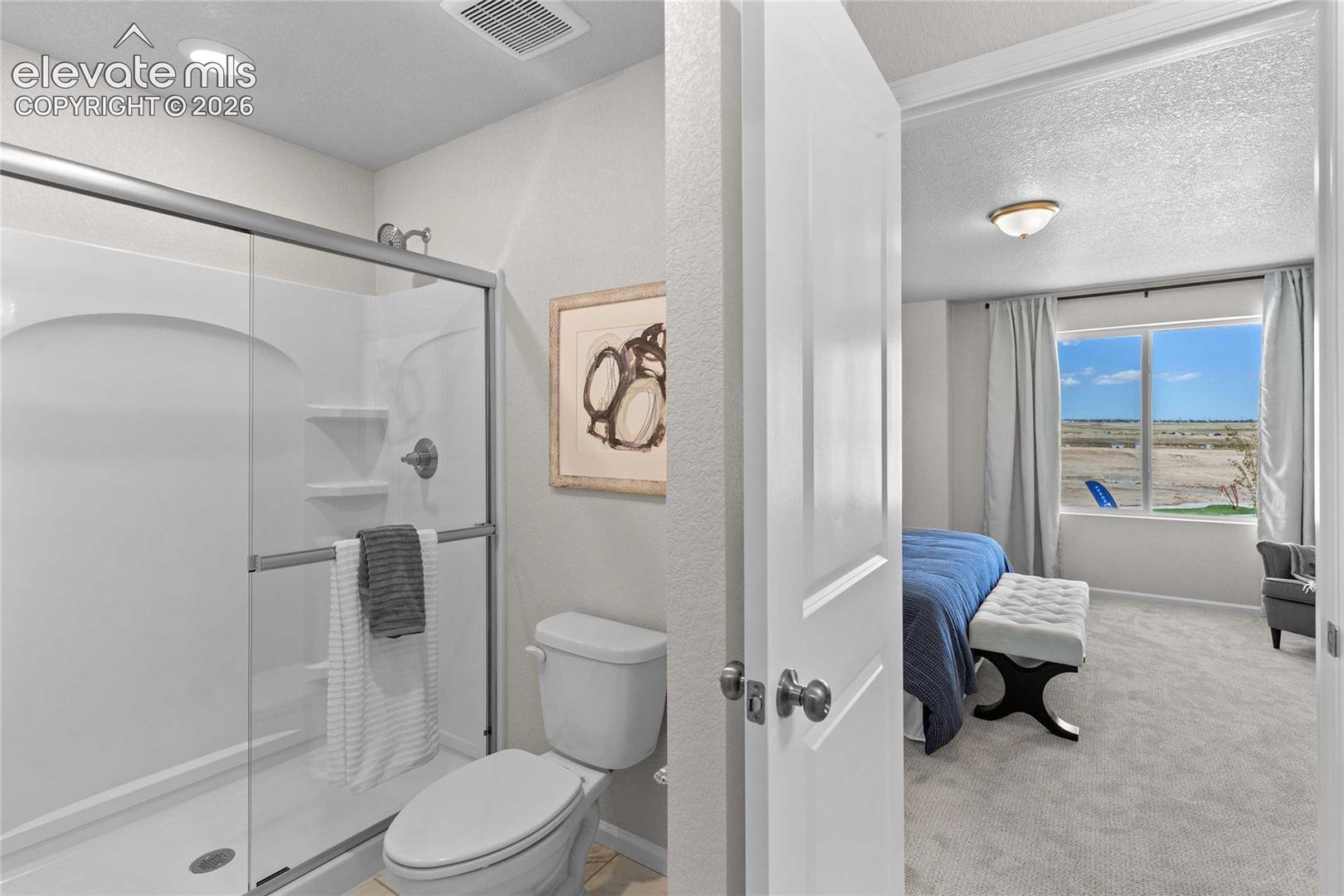 Bathroom featuring a glass-enclosed shower stall with integrated shelving, chrome fixtures, and neutral wall tones
*photos of a model home*