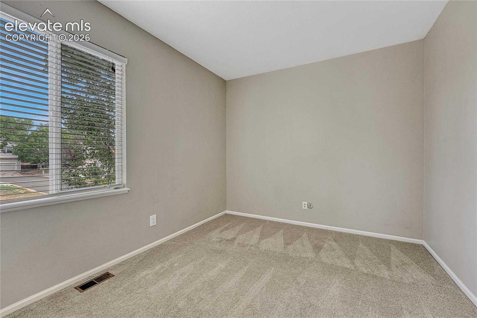 Neutral interior space featuring neutral wall paint, carpeting, and a window with horizontal blinds