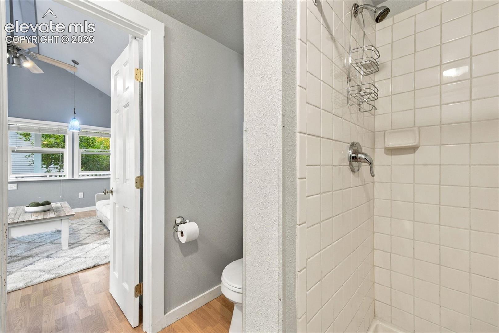 Shower stall featuring square white tile surround, chrome faucet hardware, and recessed soap dish
