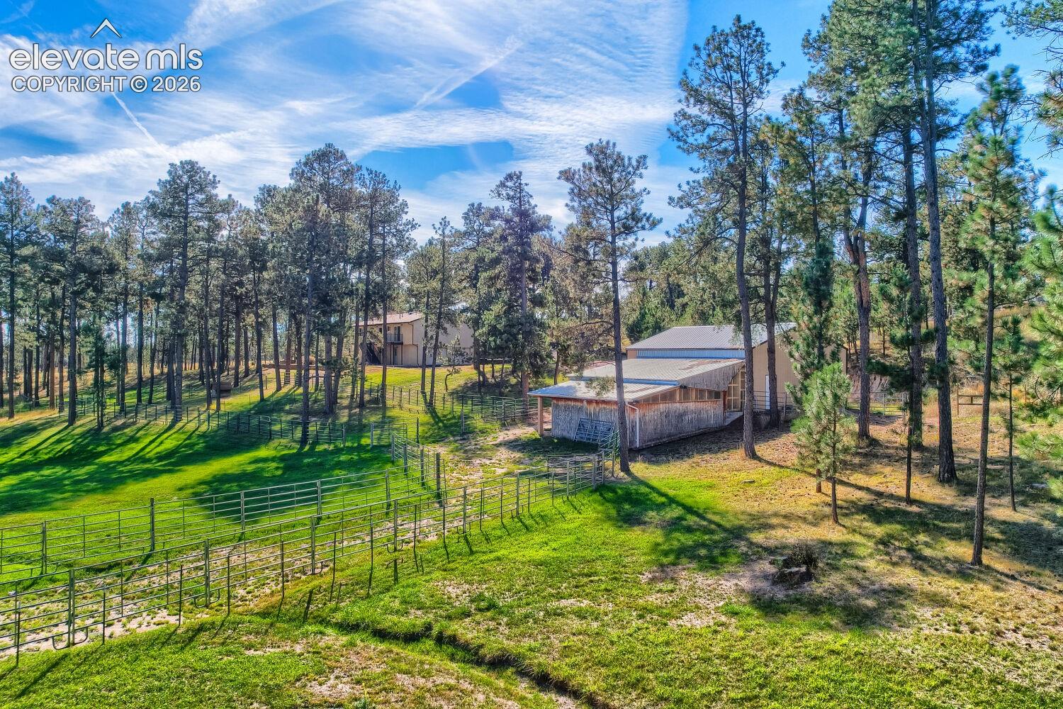 Expansive green landscape with mature trees and a fenced perimeter