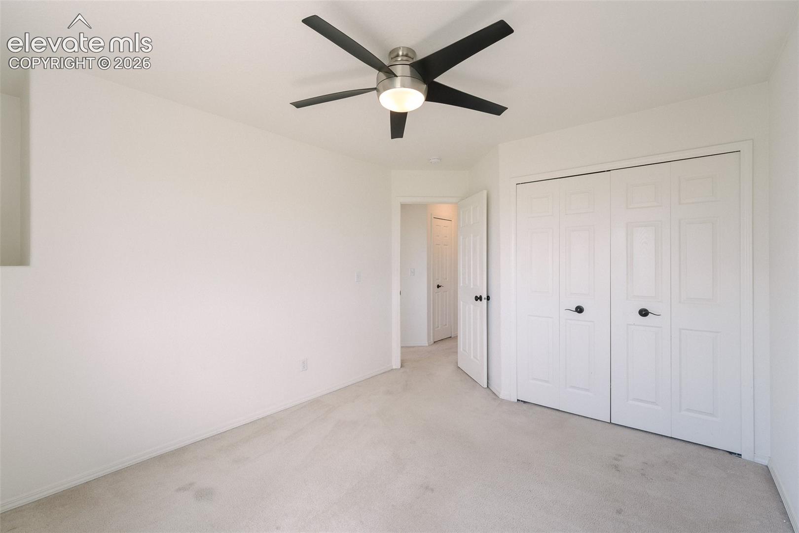 Recessed wall detail, ceiling fan with brushed nickel finish, neutral wall paint, bi-fold closet doors, light-toned carpeting