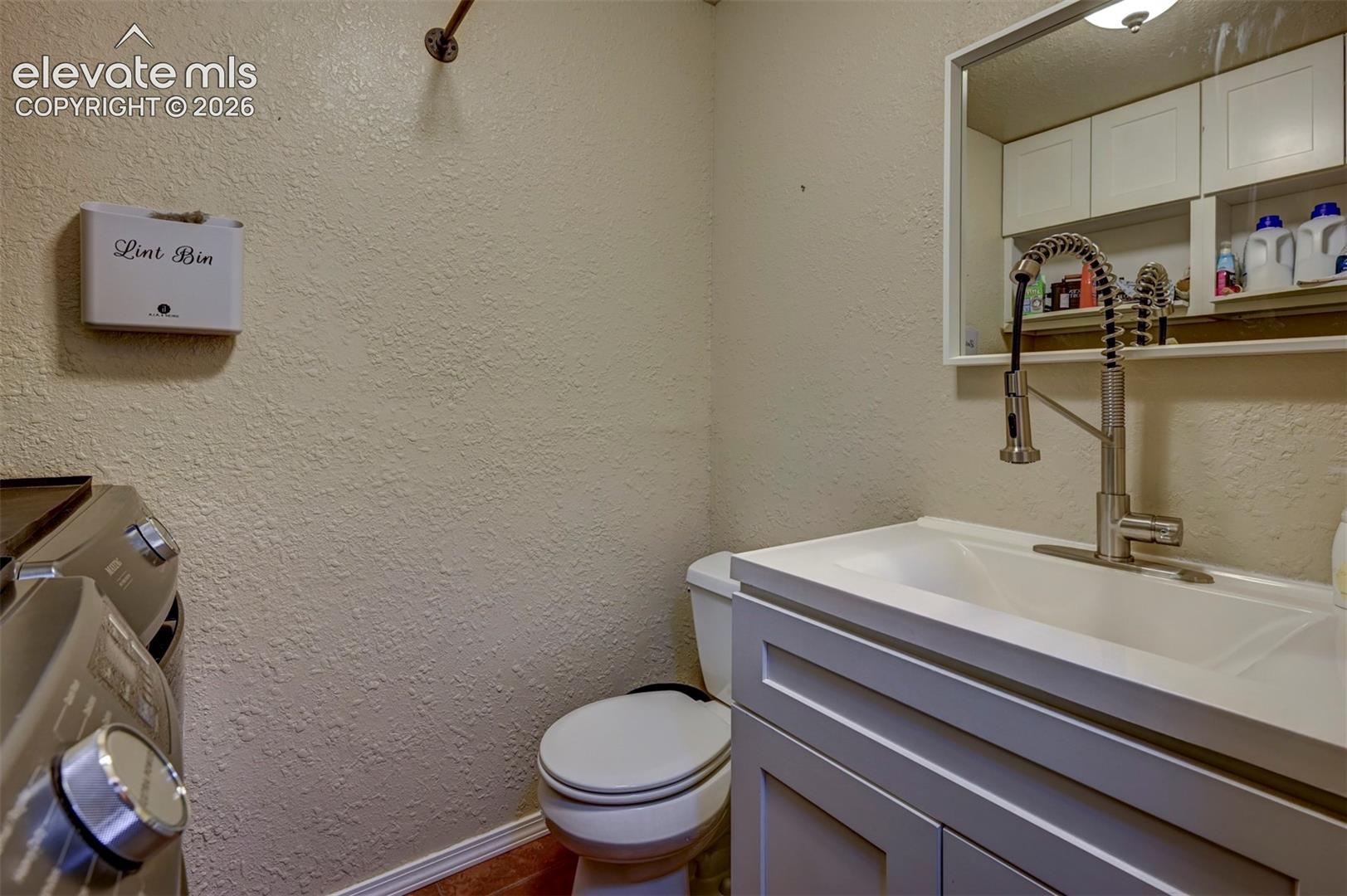Vanity with integrated sink, pull-down faucet, wall-mounted mirror, and white cabinetry