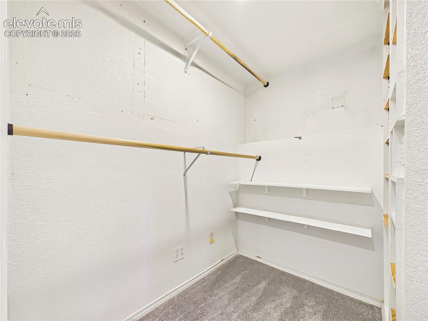 Expansive walk-in closet with built-in shelving and abundant hanging space, providing exceptional storage and organization.