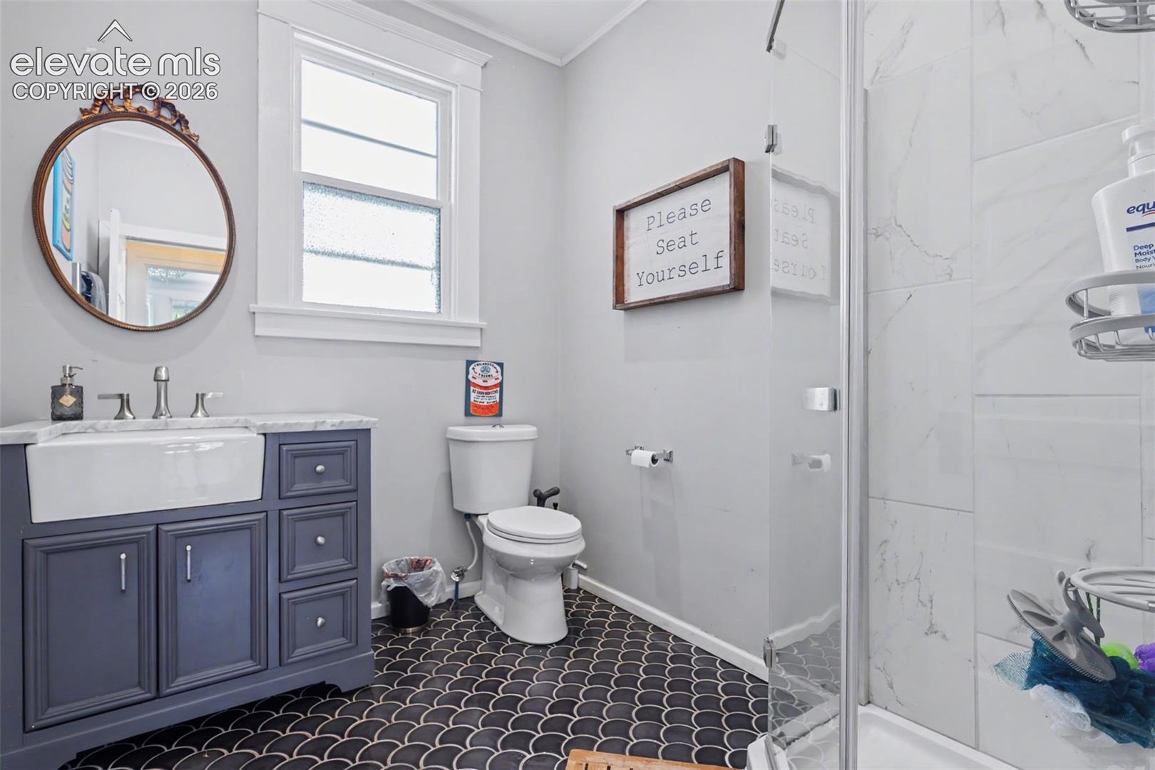 Bathroom featuring vanity, a marble finish shower, and crown molding