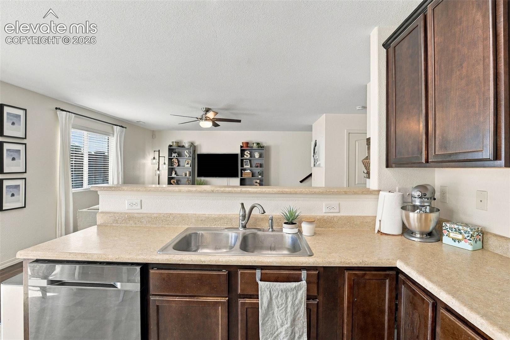 Kitchen featuring a double stainless steel sink, a stainless steel dishwasher, and dark wood-finish cabinetry