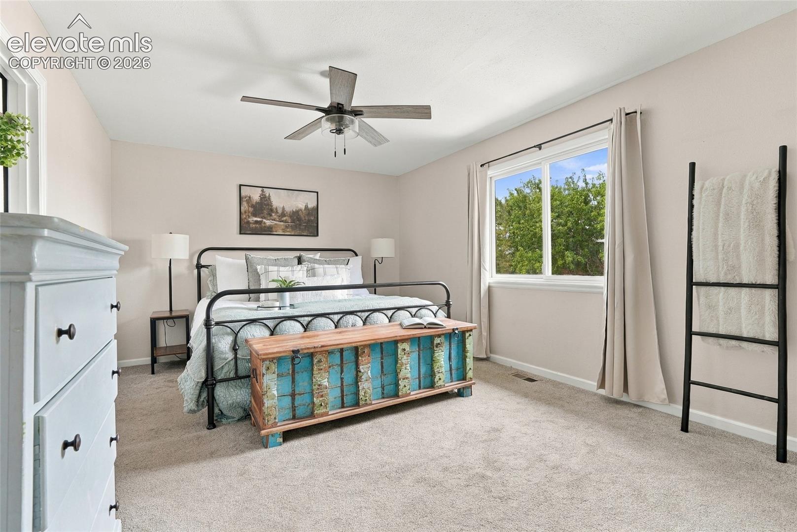 Neutral wall color, ceiling fan, window with white trim, and light-colored carpet