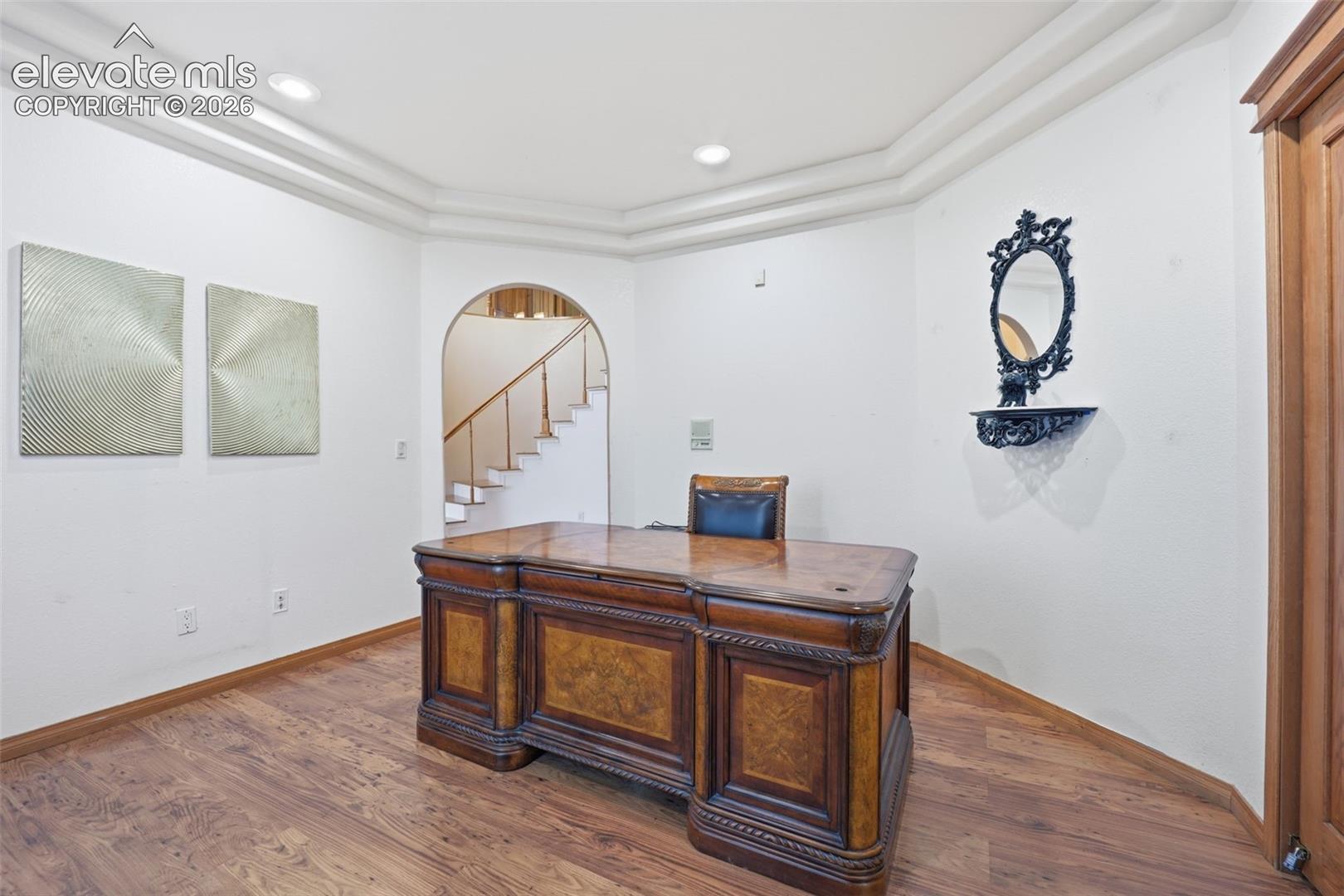 Wood-finish flooring, recessed lighting, crown molding, and an arched entryway