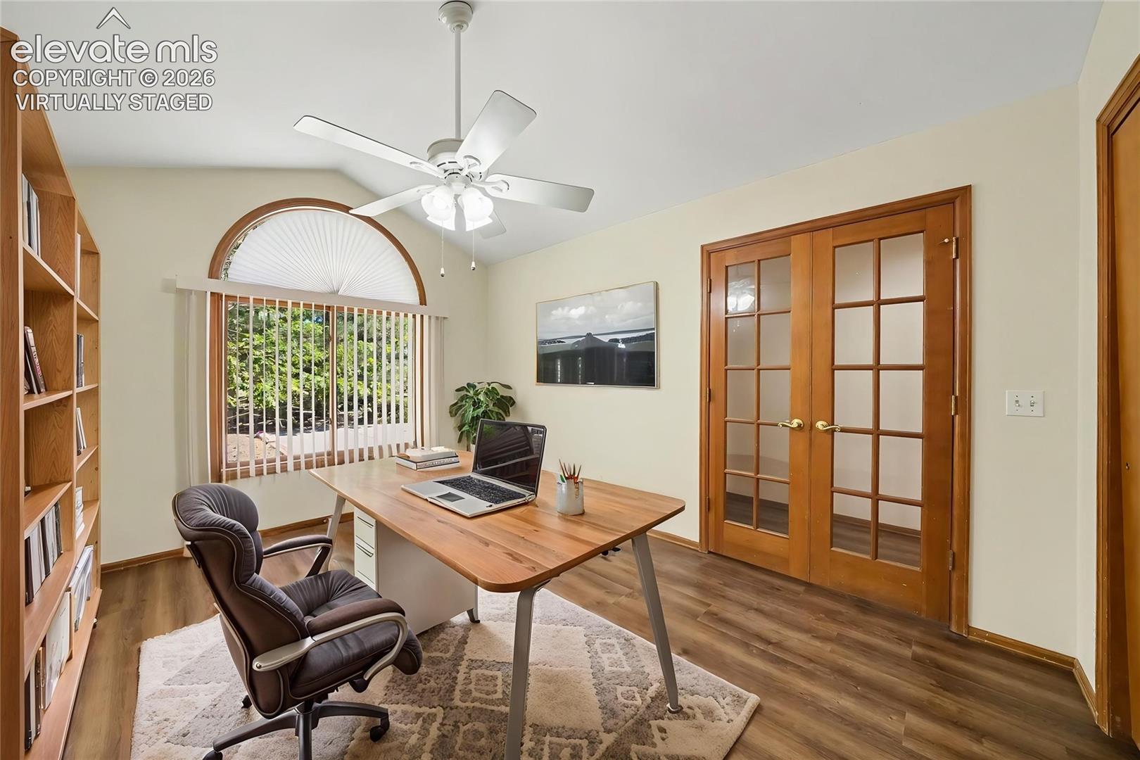 Virtually Staged. Vaulted ceiling, arched window with vertical blinds, ceiling fan, new LVP flooring, and French doors