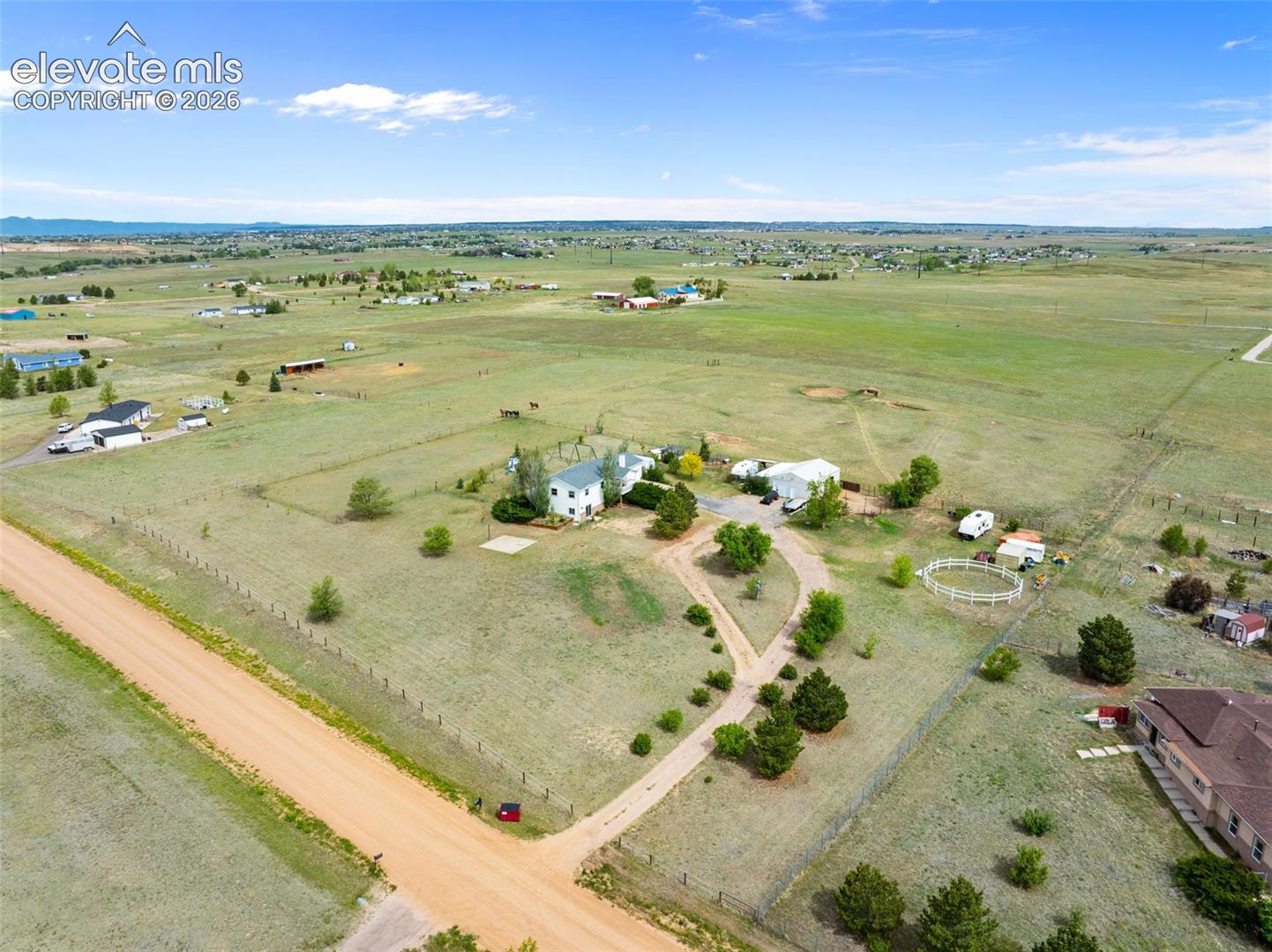 Expansive rural property featuring a main residence, multiple outbuildings, a white paddock, and extensive fenced acreage