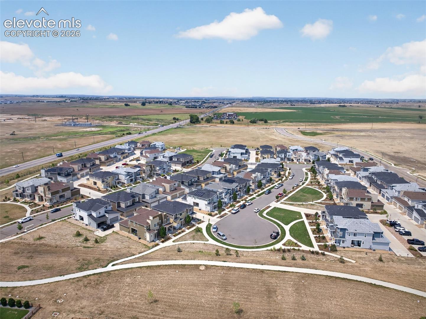 Aerial perspective of a suburban residential community featuring paved cul-de-sacs, concrete sidewalks, integrated green spaces, and multi-level detached homes