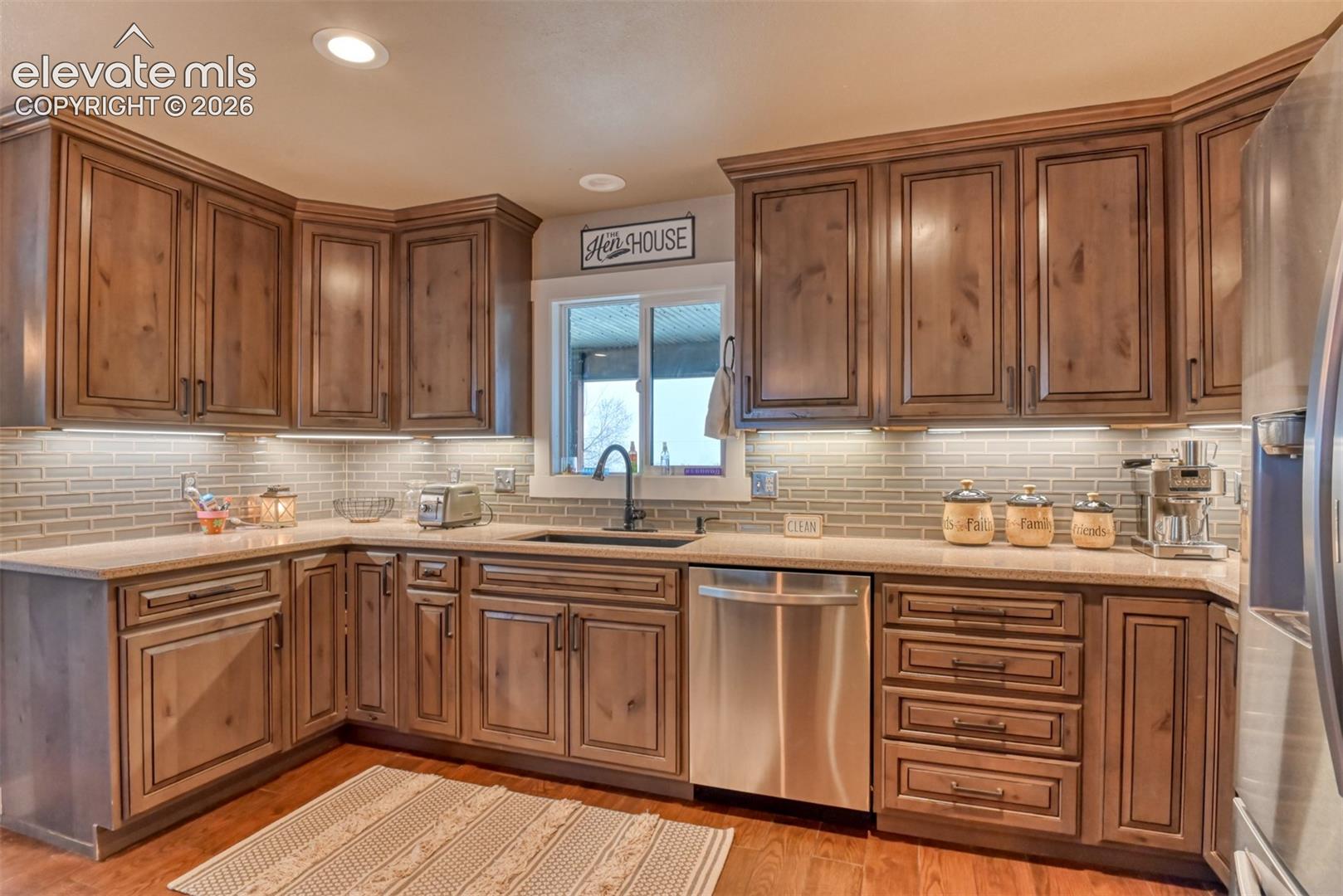 Kitchen with stainless steel appliances, light stone countertops, tasteful backsplash, light wood-type flooring, and recessed lighting