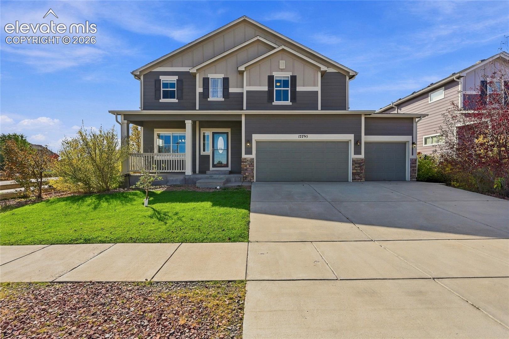 Two-story exterior featuring horizontal lap siding, stone veneer accents, a covered front porch, and a three-car garage