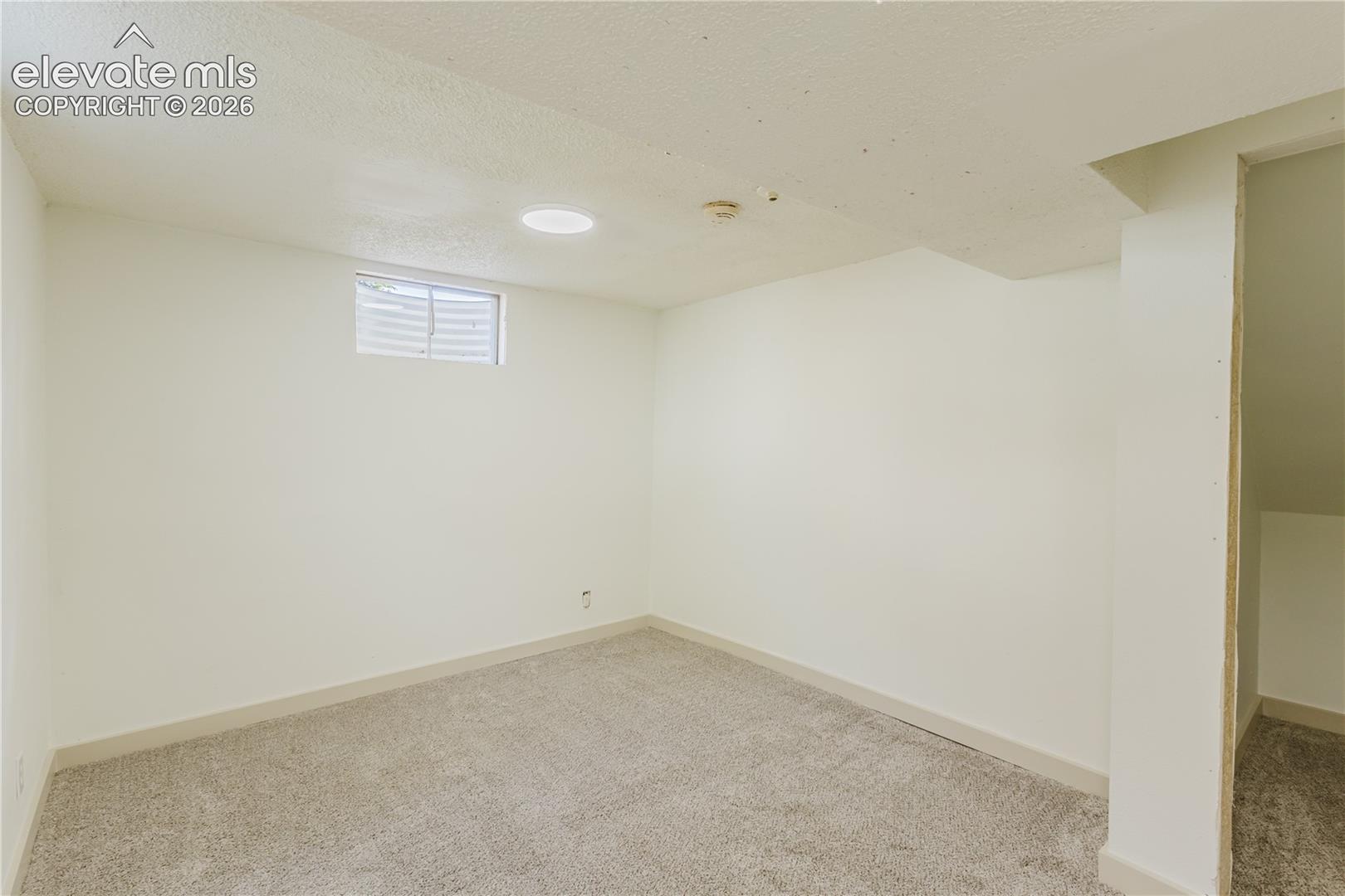 Finished room featuring light-colored carpet, white walls, a recessed light fixture, and a window