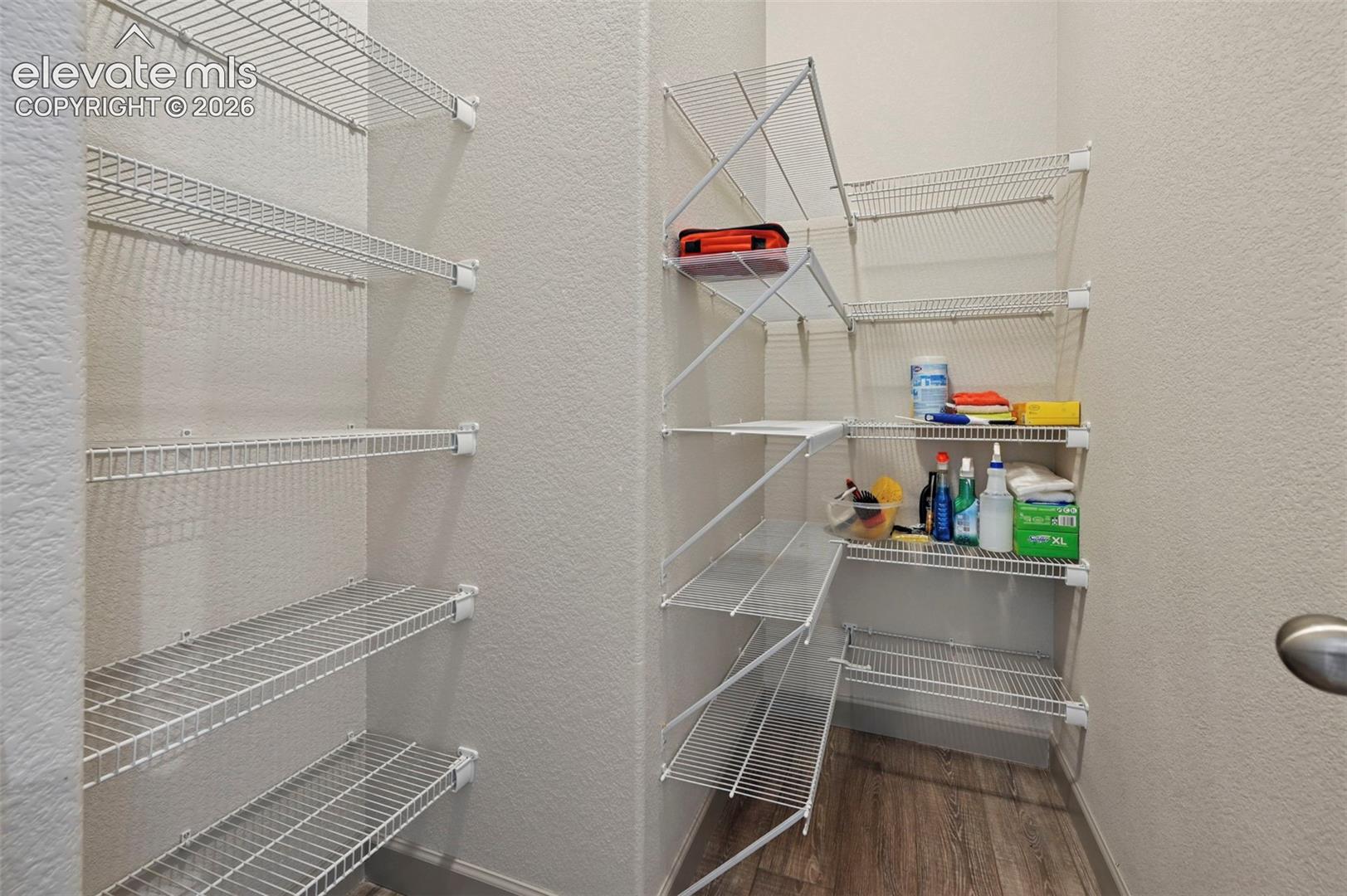 Storage area featuring multi-tier white wire shelving and wood-finish flooring