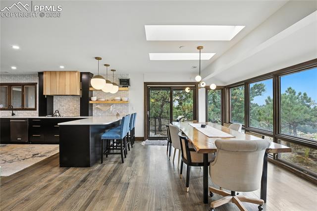 Dining room featuring dark wood finished floors, a chandelier, a skylight, and recessed lighting