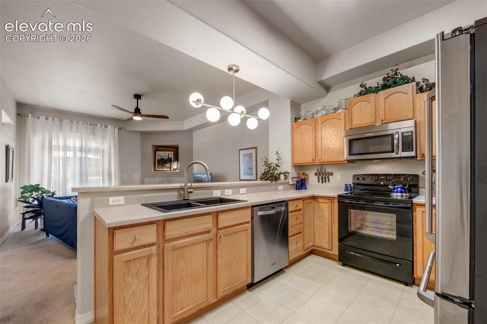 Kitchen featuring wood cabinetry, white countertops, tile flooring, and stainless steel appliances