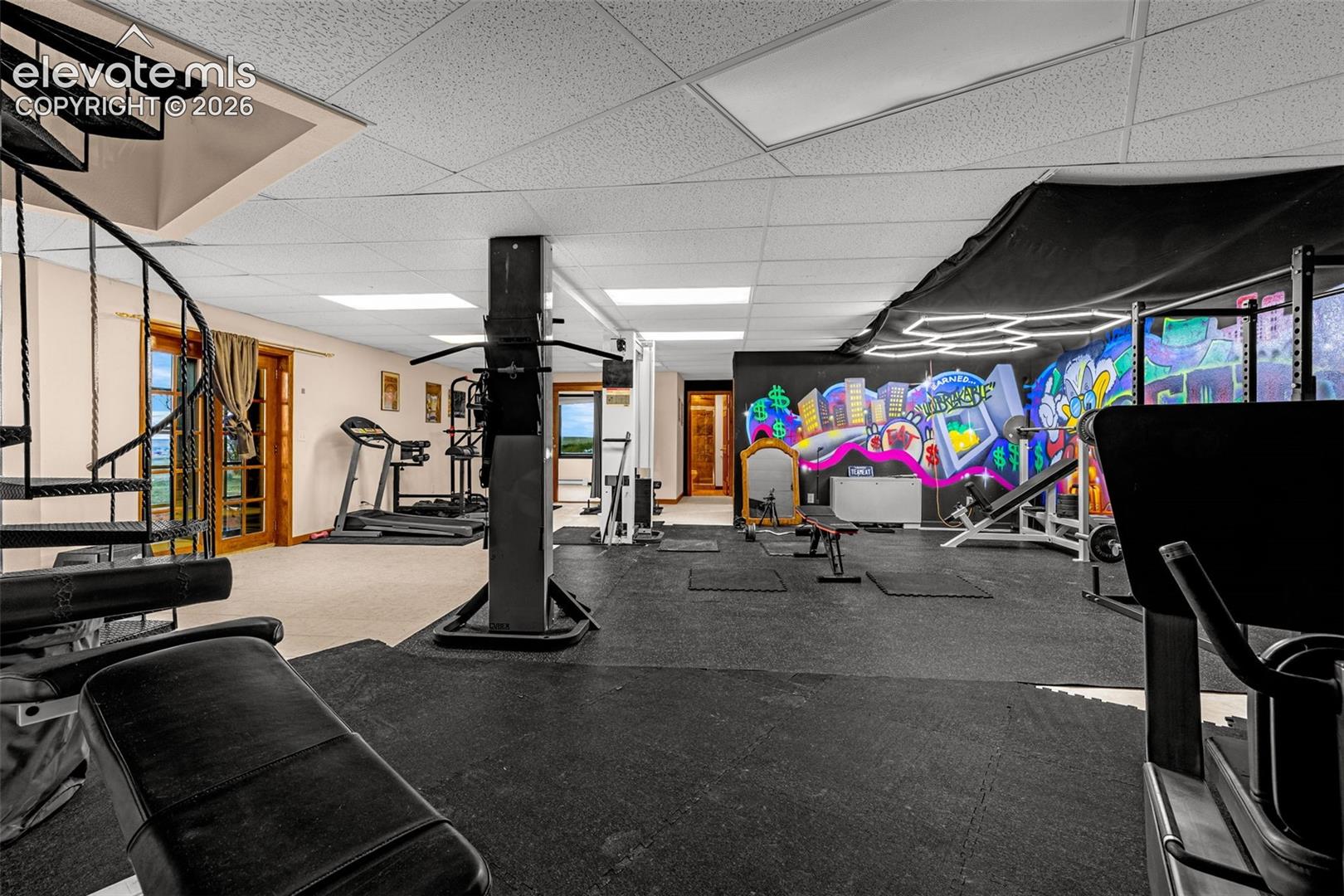 Expansive space with rubberized flooring, a decorative wall mural, recessed lighting, and a black spiral staircase