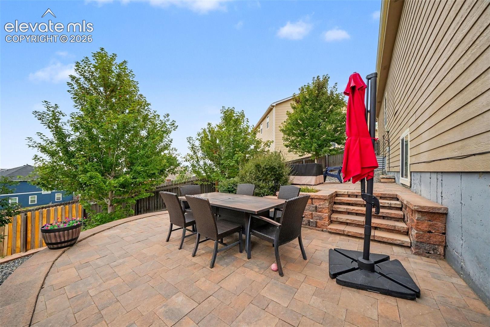 Spacious paver patio with a terraced stone retaining wall