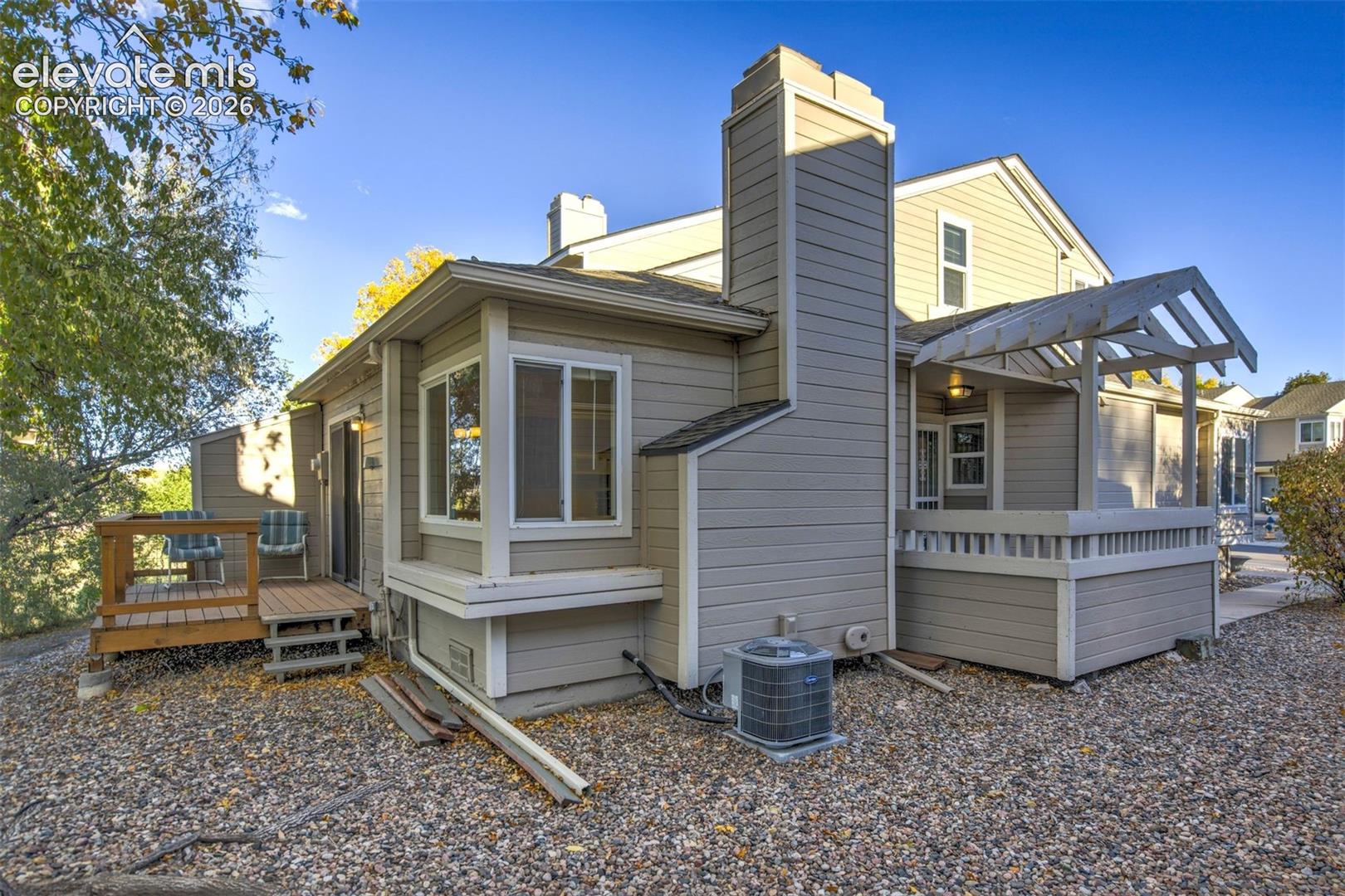 Multi-level exterior featuring horizontal siding, a prominent chimney, an attached wood deck, and a covered pergola area