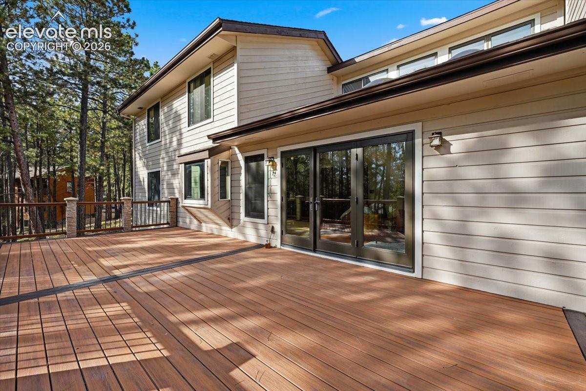 Expansive wood-finish deck with dark railing and stone-clad pillars