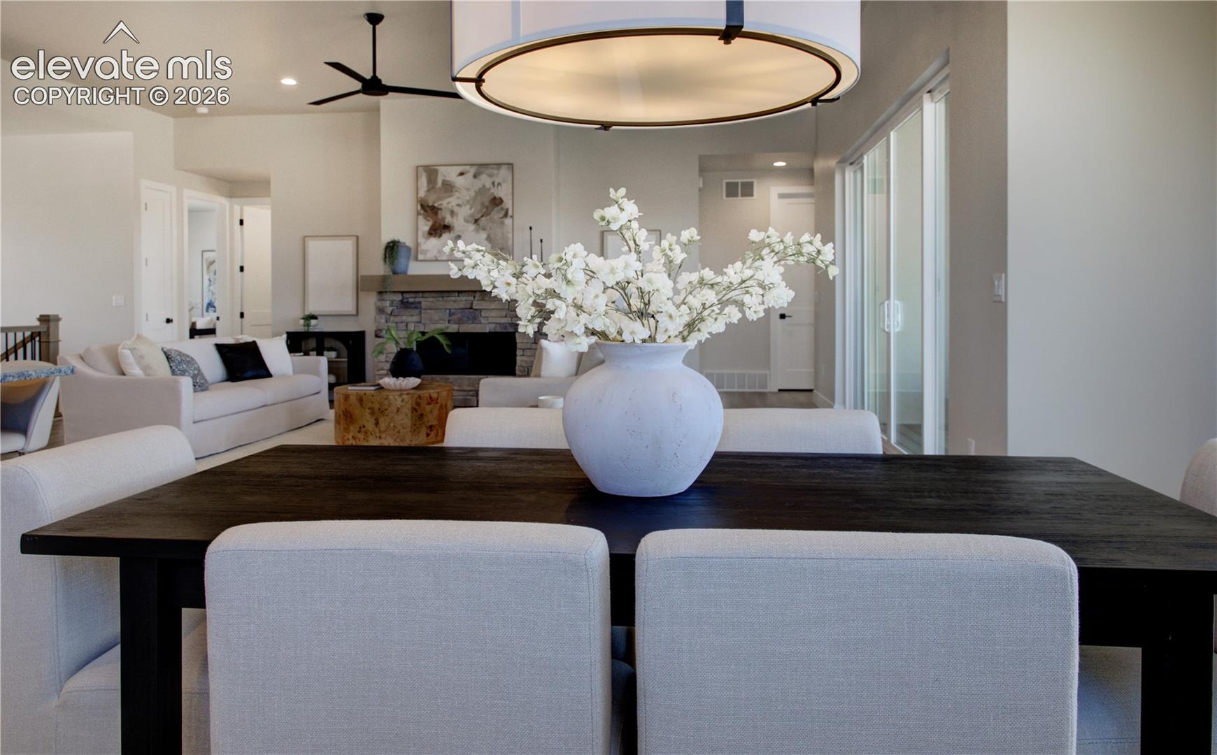 Dining space featuring a dark wood-finish table with upholstered chairs, under a contemporary drum pendant light