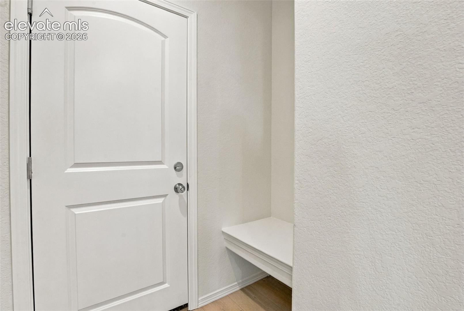 Two-panel arch-top interior door featuring a satin-nickel deadbolt and lever handle, paired with a built-in recessed bench