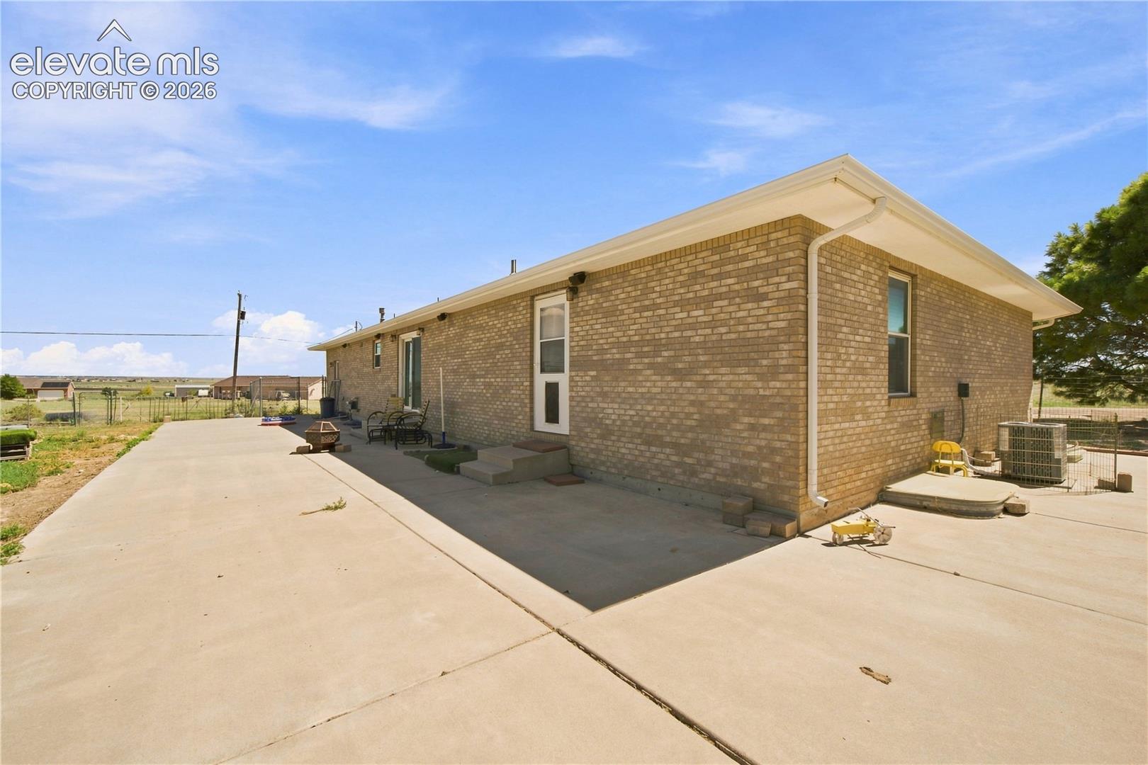 Brick exterior with a large concrete driveway and a concrete patio
