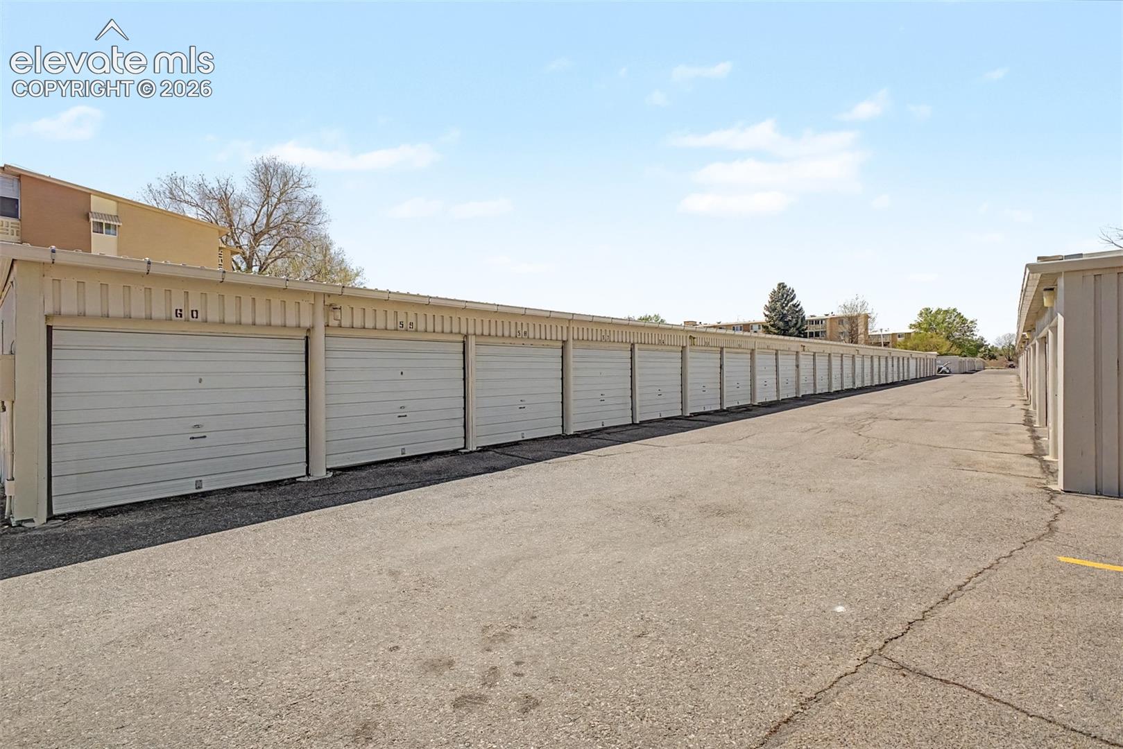 Rows of individual garage units with light-colored roll-up doors, metal siding, and asphalt drive