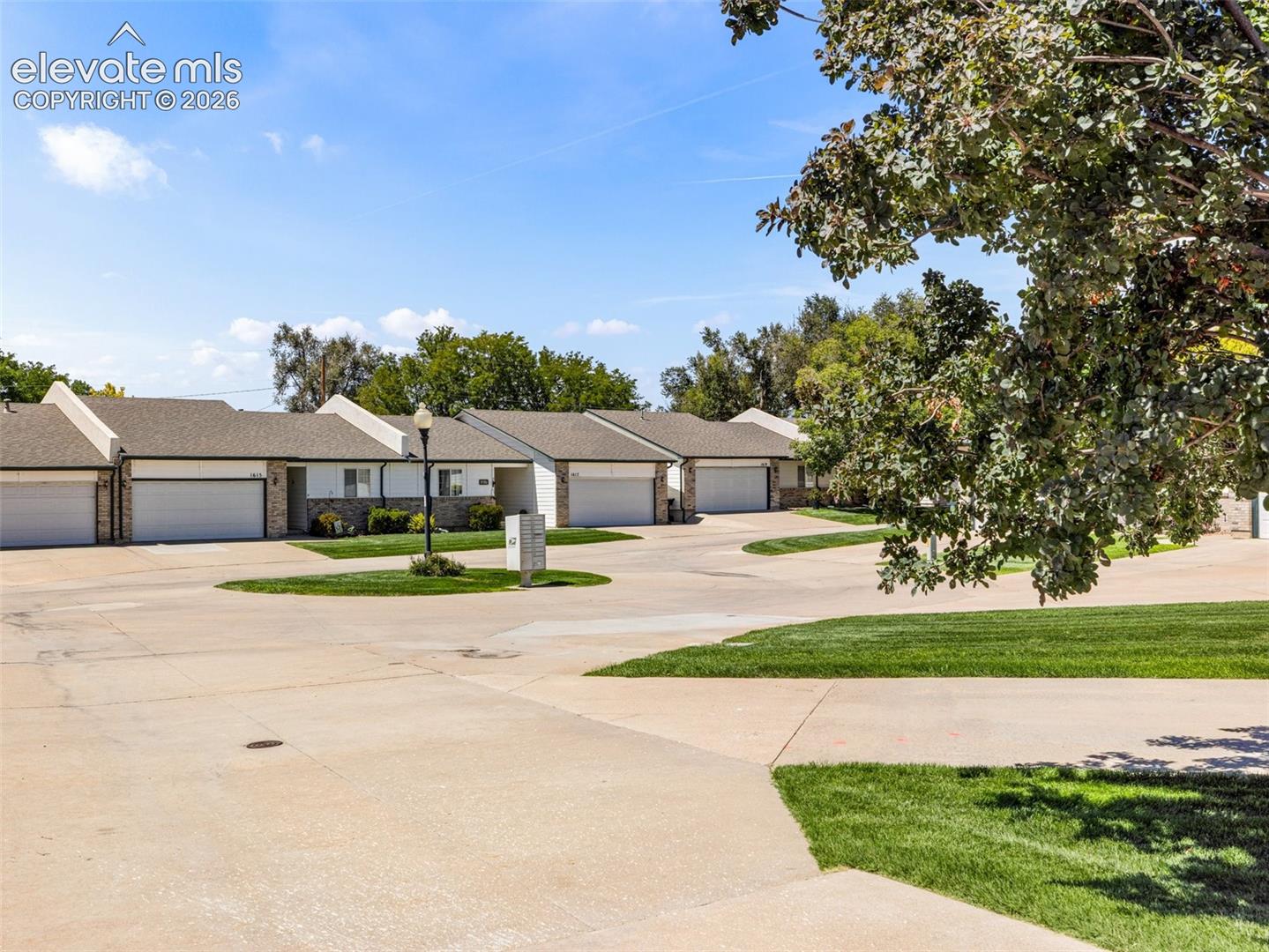 Concrete driveways with integrated landscaping, attached garages with white doors, and stone facade accents