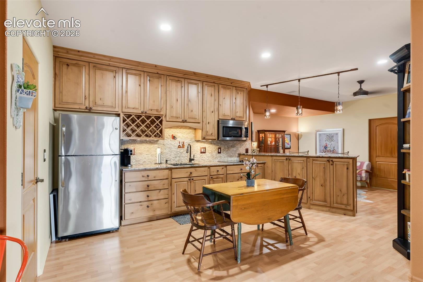 Kitchen featuring light-tone wood cabinetry, stone-finish countertops, built-in wine rack, stainless steel appliances, and recessed lighting