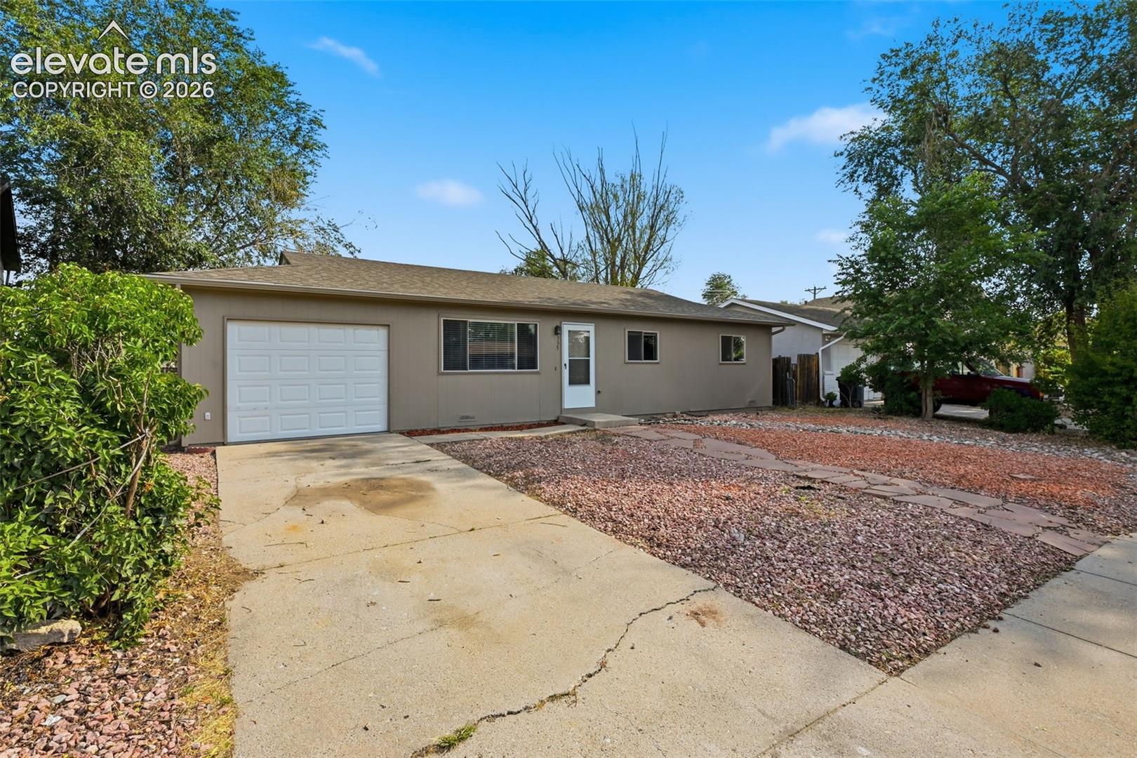 Single-story exterior with an attached garage, covered entry, and a gravel front yard