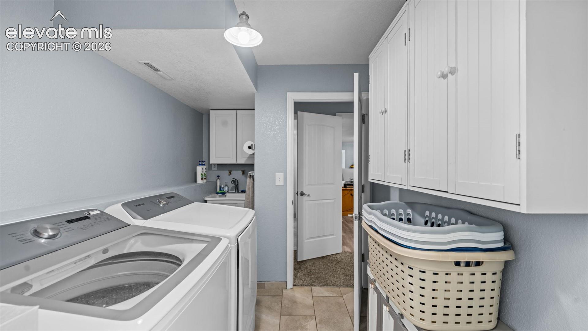 Laundry area featuring white cabinetry, a utility sink, and tile flooring