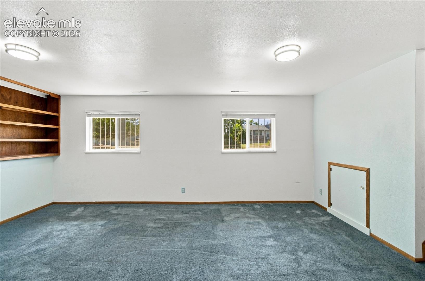 Recessed wood-finish shelving, wall-mounted flush lighting, and a textured carpeted floor