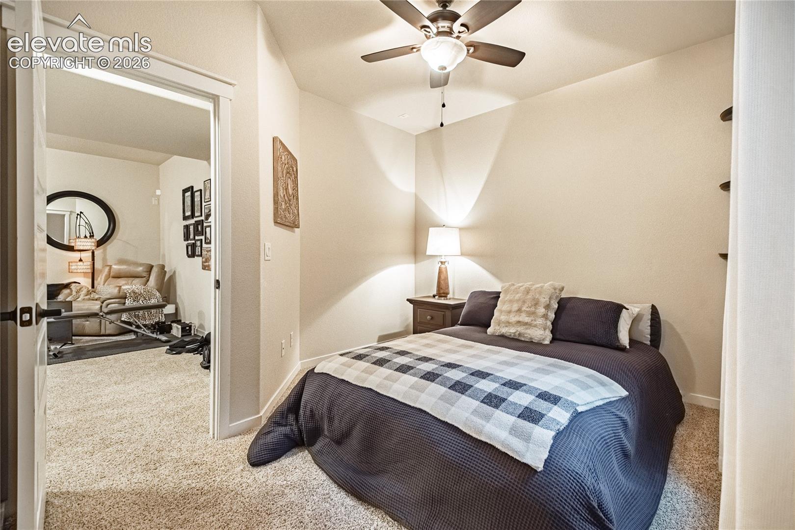Bedroom featuring wall-to-wall carpeting, a ceiling fan with integrated lighting, and built-in wall shelving