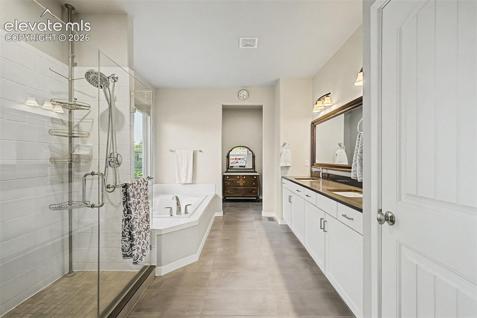 Luxurious primary bath features dual vanities, an oversized glass-enclosed shower, and beautiful finishes designed for comfort and style.