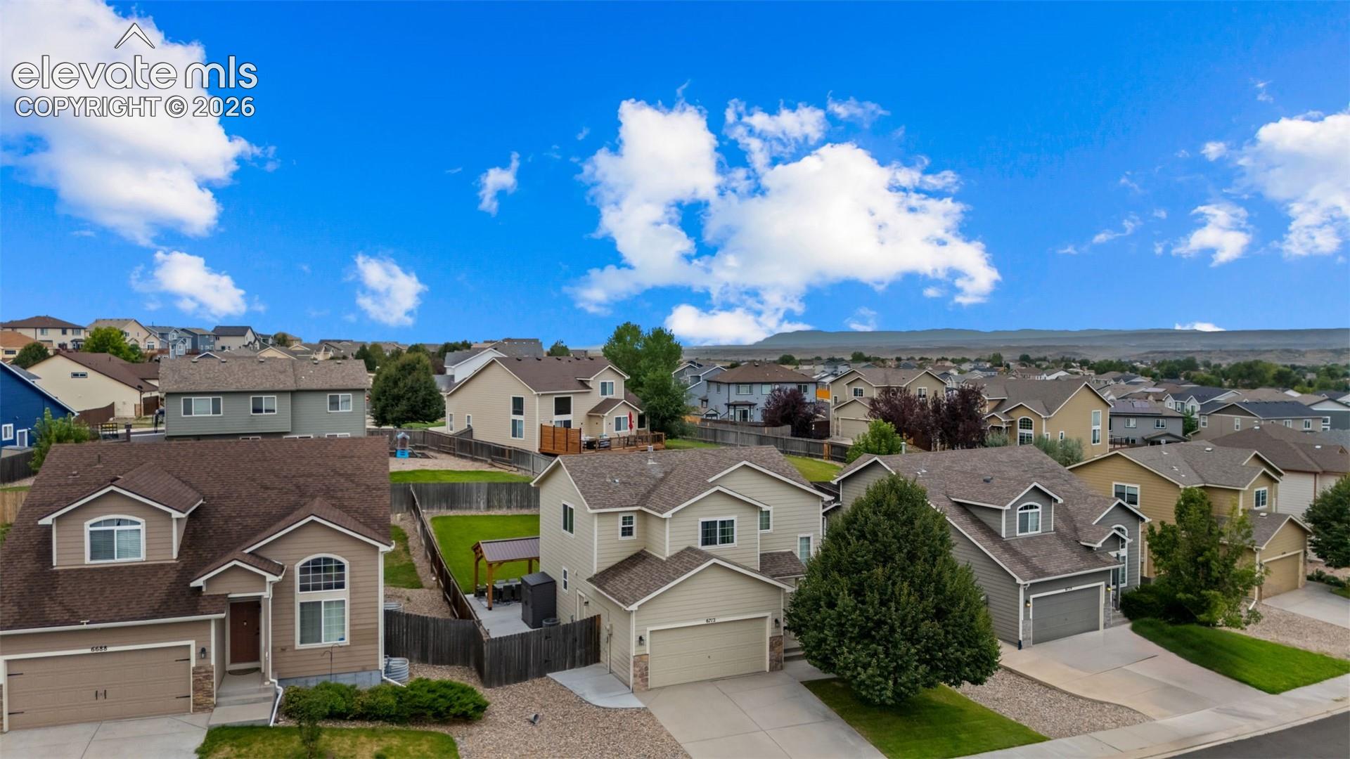 Aerial perspective featuring residential homes, paved driveways, and landscaped yards